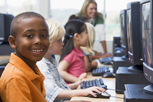 male student smiling at camera while seated in computer lab