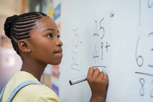 female student at whiteboard working on math equation