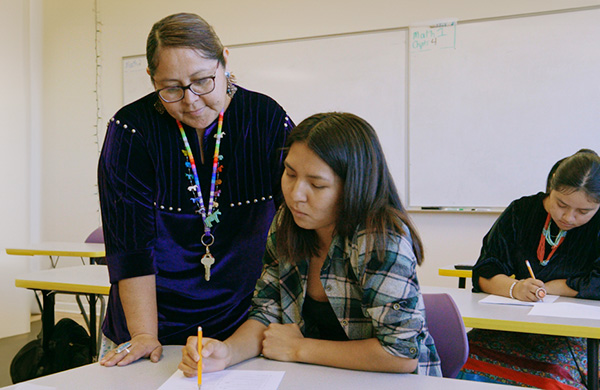 Teacher in a classroom with an indigenous student